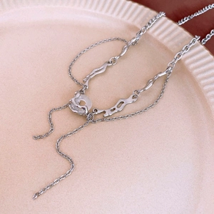 Detail of silver liquid metal star necklace with resin crystals on beige ribbed ceramic