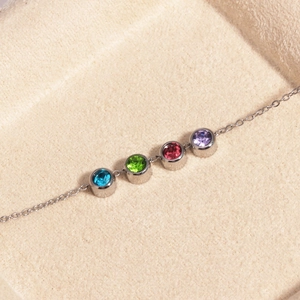 Détail de quatre breloques en zircone cubique ronde colorée sur une chaîne en argent