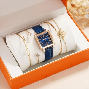 Close-up of elegant gift box featuring a square blue watch and three gold bracelets