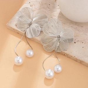 Macro detail of brushed metal ginkgo flower earrings with elegant hanging pearl pendant
