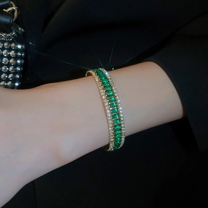 Detail of square emerald and diamond open bracelet on wrist with gold finish