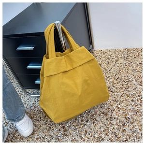 Ginger yellow nylon tote bag hanging naturally in a casual outdoor lifestyle setting