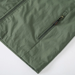 Close-up of military green outdoor jacket with zipper pocket and SPORTS puller