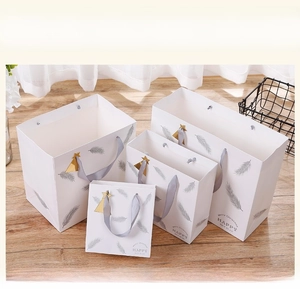 Set of four gift bags with silver feather print, gold stars and satin ribbon handles