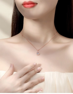 Detailed view of square rose gold pendant with dancing stone on a woman's collarbone