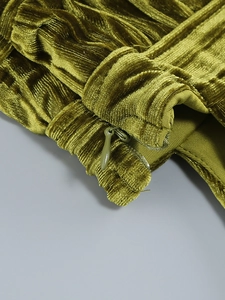 Détail macro du tissu en velours vert olive avec plis et fermeture éclair invisible