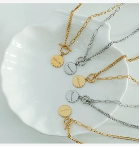 Detail of gold and silver OT buckle necklaces with Beloved engraved round pendants