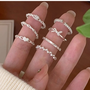 Six-piece silver ring set featuring twist and heart designs worn by a model