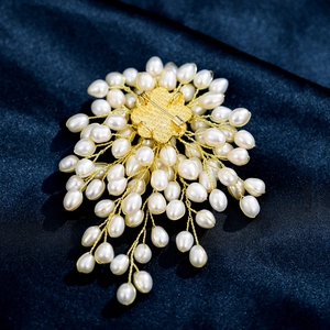 Macro detail of hand-woven natural freshwater pearl brooch with gold pin on blue silk