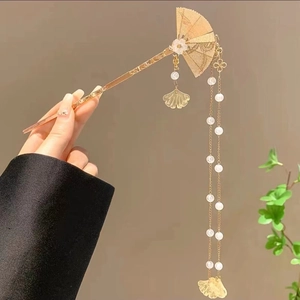 Détail d'une épingle à cheveux dorée avec motif éventail, feuilles de ginkgo et perles