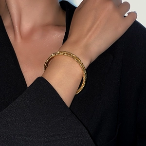 Detailed close-up of textured gold multi-layer bracelet with sparkling frosted finish