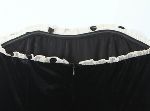 Détail de robe en velours noir avec col à volants à pois blancs et fermeture éclair au dos