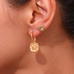 Close-up of woman wearing vintage 18K gold plated sun and flower hoop earrings