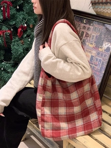Large red and beige plaid tote bag styled for winter commuting in a festive setting