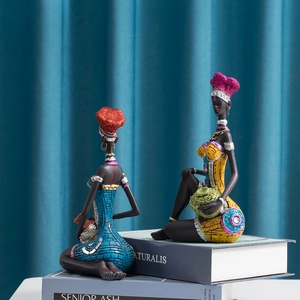 Close-up of two seated African resin figurines with vibrant blue and yellow beaded details