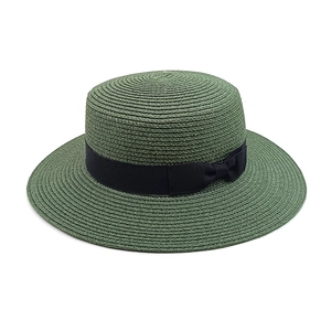Detail of dark green boater hat featuring fine woven straw texture and black bow ribbon