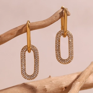 Detail of 18K gold-plated earrings with pave-set zircons on a natural branch