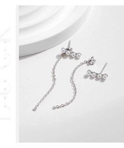 Macro detail of 925 silver pearl drop earrings with elegant long metal fringe tassels