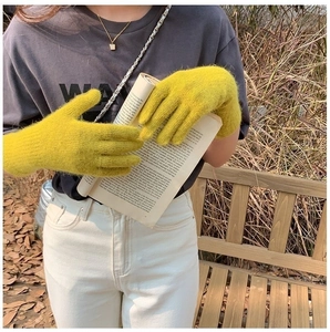 Detail shot of warm yellow plush knit mittens being worn by a model in outdoor setting