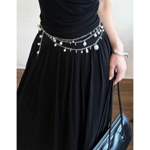 Double-layered shell and pearl tassel waist chain on a black dress for a chic look