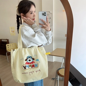 Detail of cute puppy embroidery on a light yellow canvas tote bag with drawstring closure