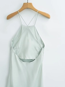 Detail view of mint green satin dress featuring delicate criss-cross back straps on a hanger