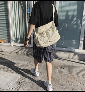 Street style shot of cream canvas crossbody bag with large capacity and double front pockets