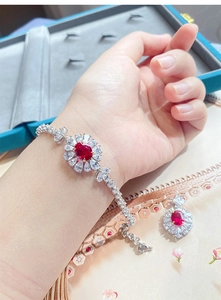 Dettaglio di un set di gioielli in tormalina rossa con design a girasole sulla mano