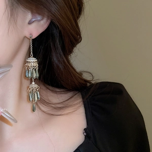 Detail of vintage gold tassel earrings with gray teardrop beads on a model profile