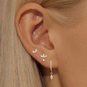 Close-up of gold ear piercing set with clear zircons on model with blonde hair