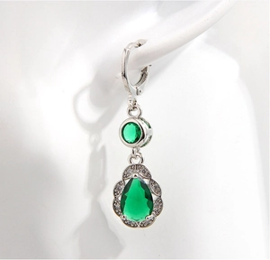 Detailed view of silver copper earrings featuring a pear-shaped green zircon stone