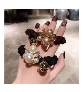 Detail of luxury silk scrunchies with champagne pearls and sparkling crystals in hand