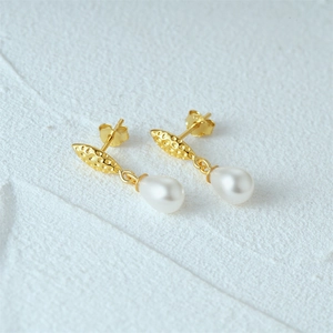 Macro shot of S925 sterling silver golden leaf earrings with elegant white teardrop pearls