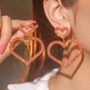 Macro shot of oversized layered heart earrings with sparkling crystals and rose gold finish