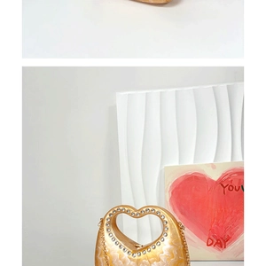 Detail of gold evening bag with rhinestone-encrusted heart handle and marble texture finish