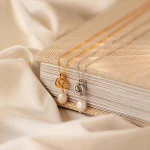 Detailed view of pearl pendant necklaces in gold and silver finish on silk fabric