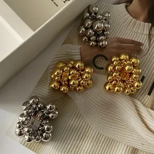 Close-up of chunky gold and silver metallic ball cluster earrings with 925 silver needle