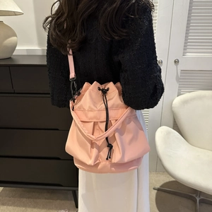 Sac seau en nylon rose à cordon porté en bandoulière dans un décor décontracté