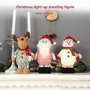 Nahaufnahme von leuchtenden Weihnachtsmann- und Rentier-Strickpuppen auf dem Kaminsims