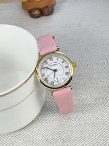 Detailed view of pink leather strap and gold watch dial with Roman numerals