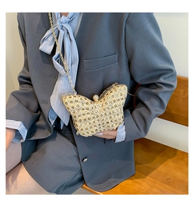Détail d'une pochette papillon en paille avec chaîne dorée et fermoir à perles