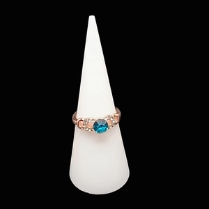 Anello in oro rosa con pietra blu e diamanti bianchi su supporto conico bianco