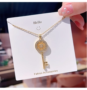 Detailed view of a gold key pendant with sparkling zircons and a fine chain necklace