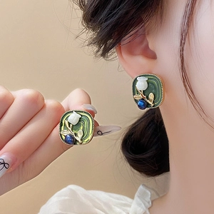 Detail of vintage green square earrings with white floral design and blue bead accent