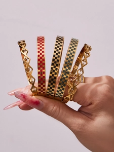 Detail view of gold checkered enamel bracelets and hollow diamond geometric bangles