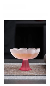 Frosted glass tea cup with lotus design and vibrant red base in close-up detail