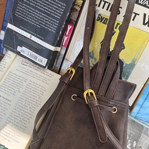 Dettaglio dello zaino vintage in pelle marrone con chiusura a coulisse e fibbie dorate