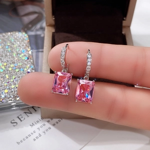 Detailed close-up of silver drop earrings with large rectangular pink zircon stones