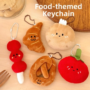 Detail showing five assorted plush food keychains including pretzel and croissant on a table