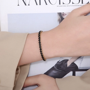 Detail of 4mm gold-plated tennis bracelet with black cubic zirconia on model's wrist